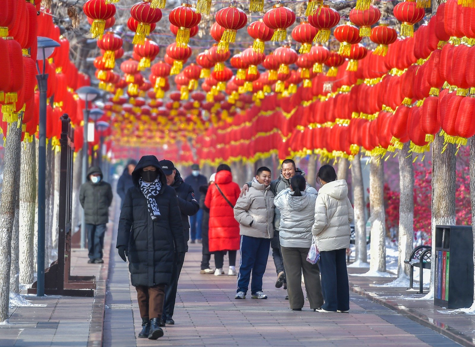 在中国新疆乌鲁木齐市人民公园，市民从“灯笼长廊”下走过。农历新年来临，该公园用中国结、灯笼墙搭建起红色主题的“灯笼长廊”，增添年味。（图取自中新社）